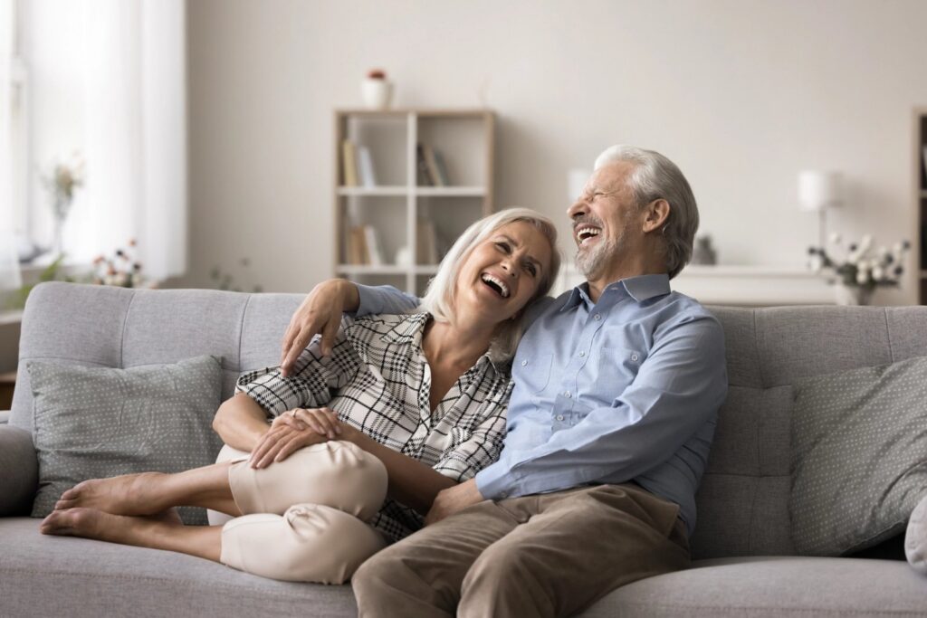 Partial Dentures In Trinity: Comfort, Fit, And Smart Upgrades Over Time An older couple laughing heartily on a sofa.