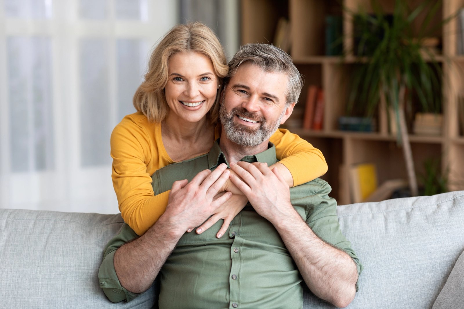 A smiling couple embraces while sitting on a sofa.