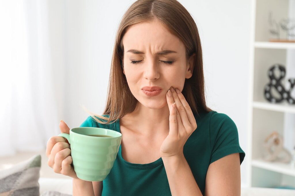 When Seconds Count: Why Immediate Attention for Dental Emergencies Is Crucial a woman is holding a cup of coffee and having a toothache .