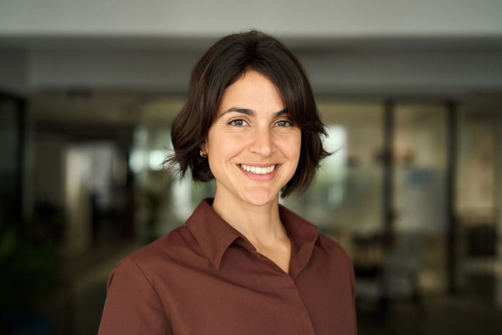 a woman in a brown shirt is smiling for the camera .