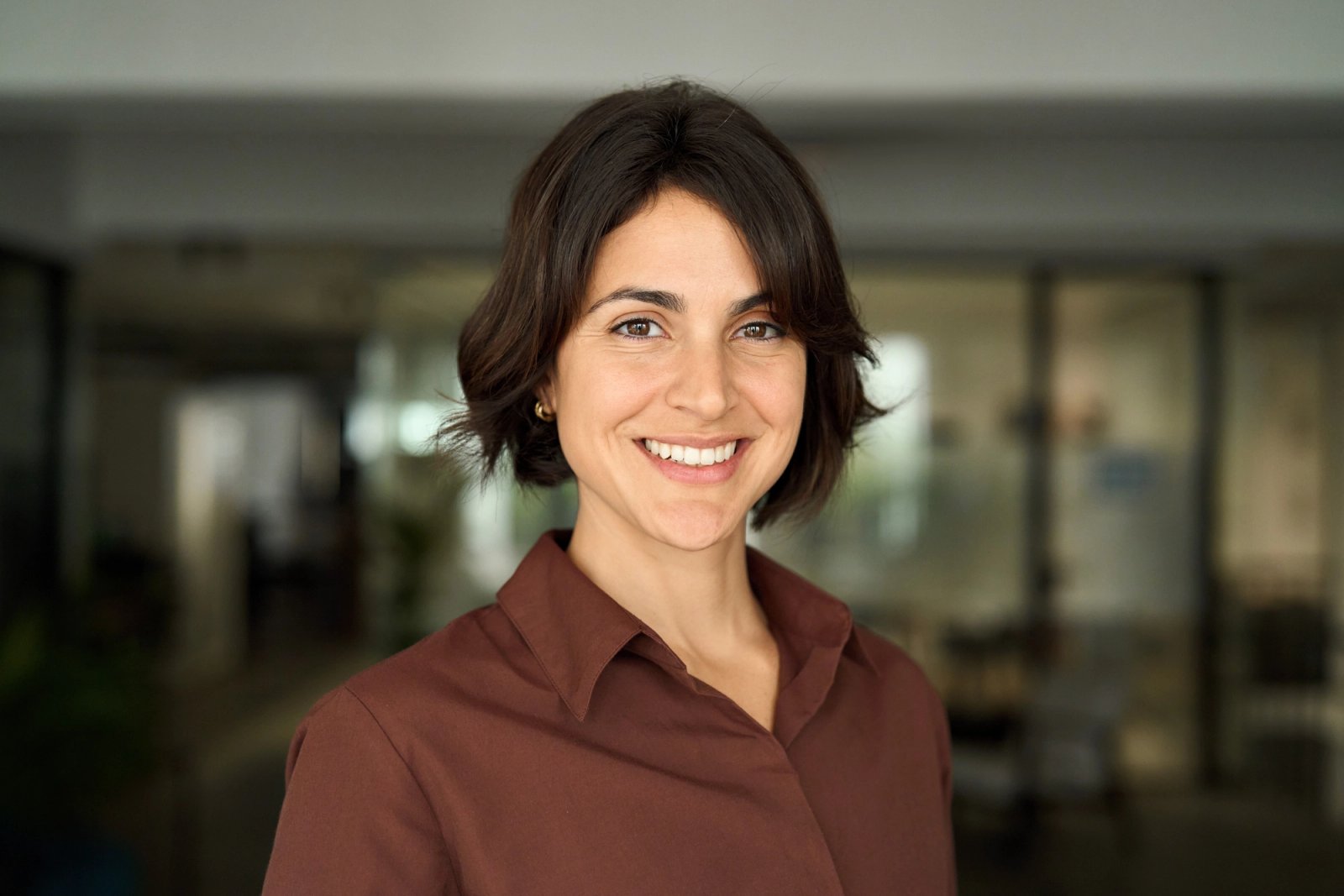 a woman in a brown shirt is smiling for the camera . a woman in a brown shirt is smiling for the camera .