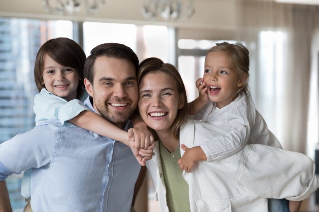 Why Routine Dental Cleanings Matter More Than You Think a happy family is posing for a picture together in a living room .