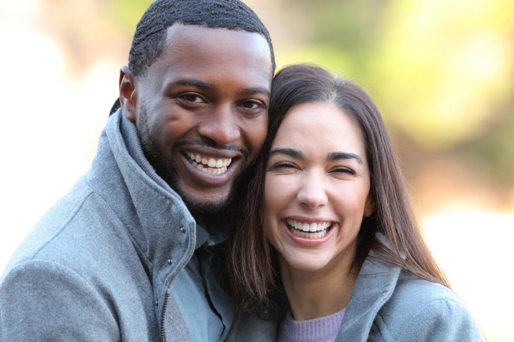 Dental Implants In Trinity: Why A Strong Foundation Matters When Replacing Missing Teeth A smiling man and a laughing woman in gray coats.