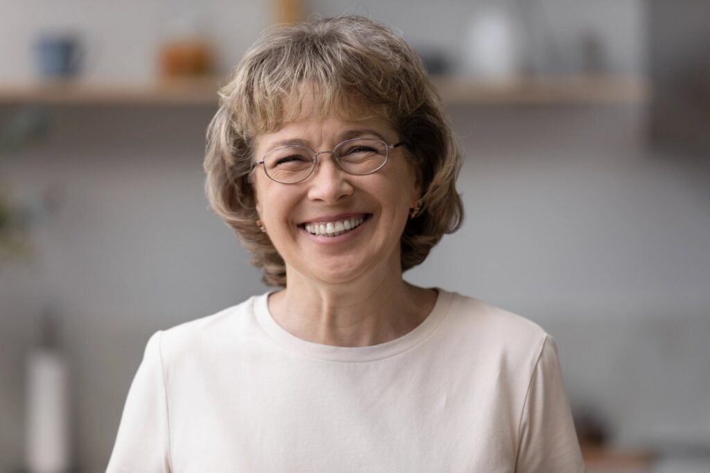 Dentures and Partial Dentures: A Comfortable Path Back to a Full Smile an elderly woman wearing glasses is smiling for the camera .