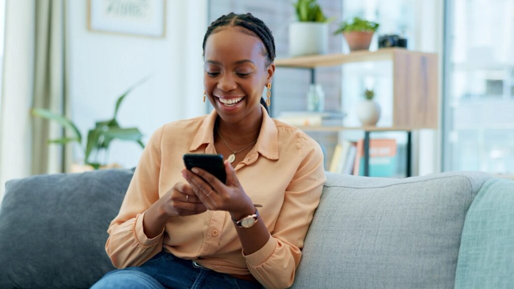 All-on-X Fixed Implants: A Confident, Full-Arch Smile That Feels Like Your Own a woman is sitting on a couch looking at her cell phone .
