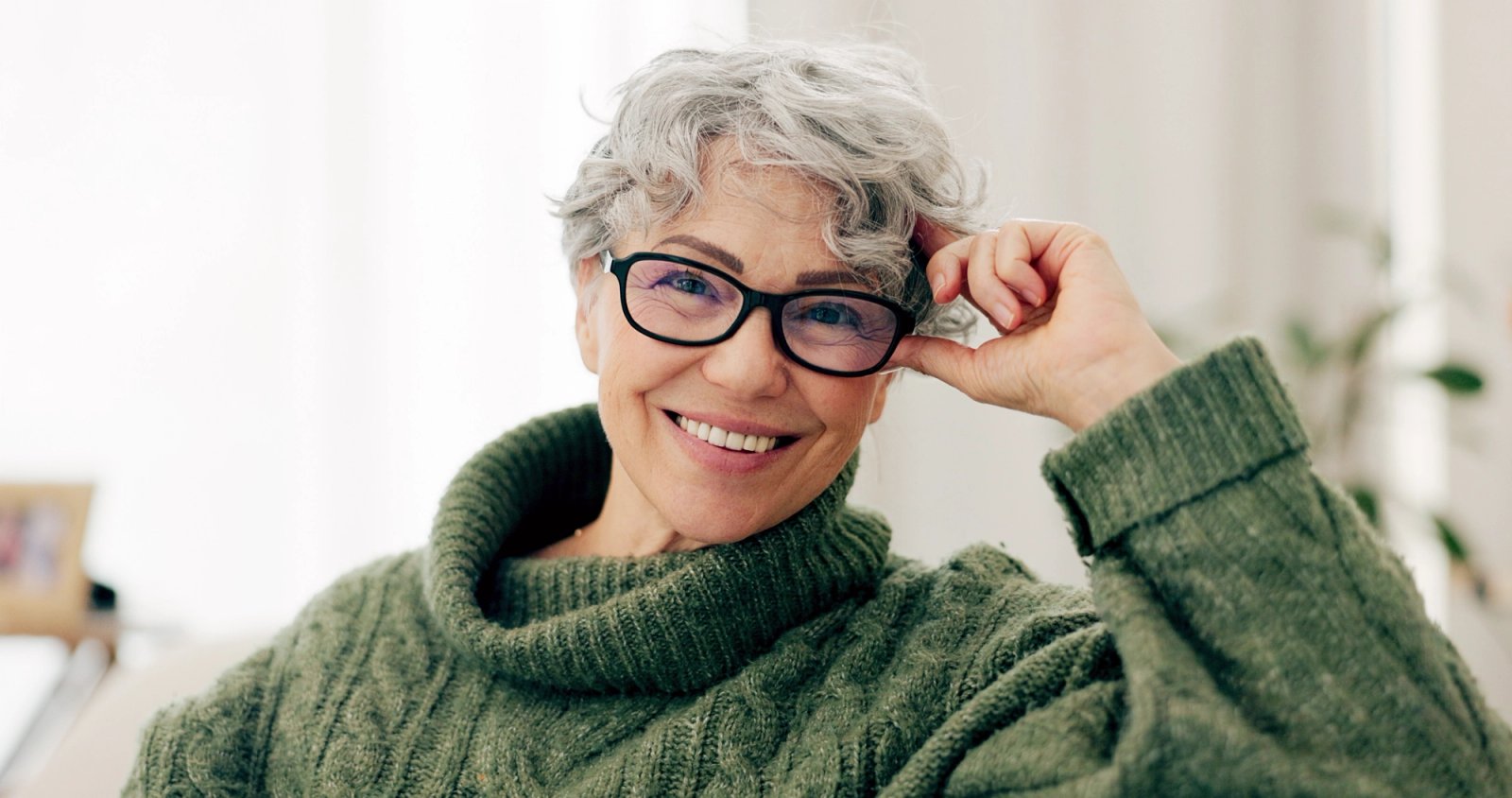 an older woman wearing glasses and a green sweater is smiling . an older woman wearing glasses and a green sweater is smiling .