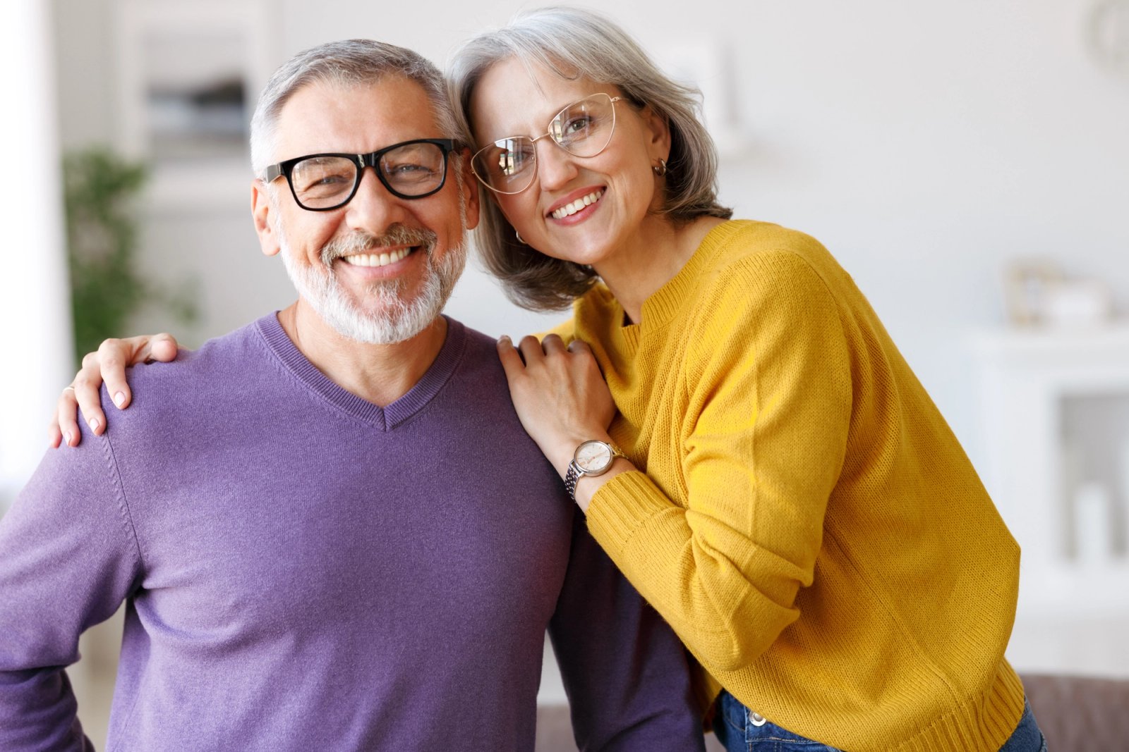 Smiling older couple with woman's arm around man.
